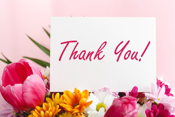 Thank you card in beautiful flowers bouquet on pink background. White blank card with space for...