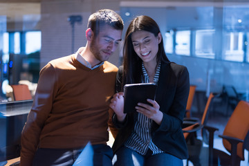 Two focused young business colleagues talking over a digital tablet while having a meeting together in a modern office