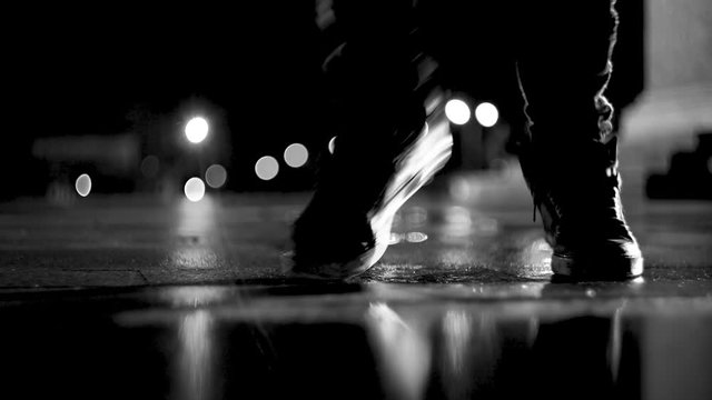 Guy dancing on the street at night. Close-up of feet