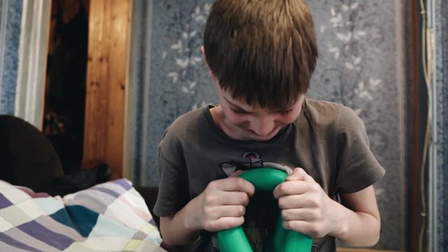 The boy squeezes the exerciser hand. Sporty boy