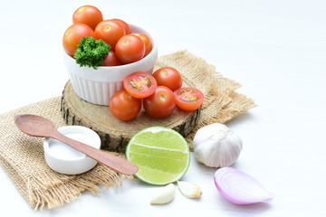 Fresh cherry tomato, displayed in containers on white wooden background