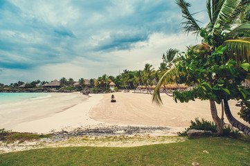 Tropical beach panorama with deckchairs, umbrellas, boats and palm tree