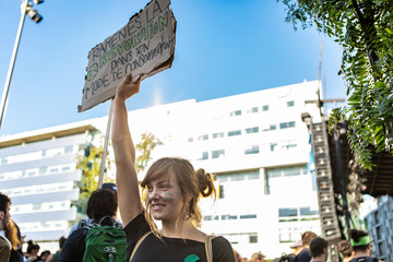 A low angle shot of a climate warrior girl, smiling during environmental protest with sign saying bring back the revolution in your consumption trend