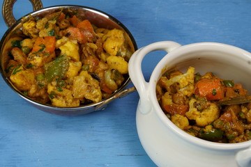 Mixed vegetable curry in a dish on a wooden blue background, with copy space.