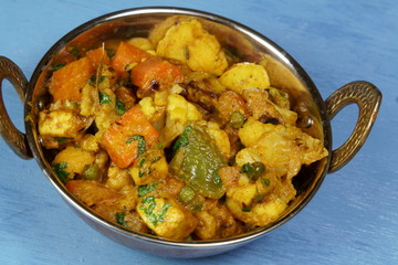 Mixed vegetable curry in a dish on a wooden blue background, with copy space.