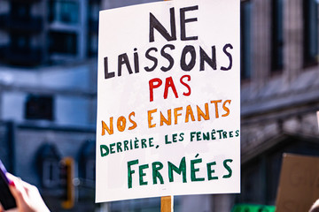 A close up shot of a French sign saying do not leave our children behind closed windows, as protestors march for zero emissions and climate change