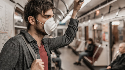Close up of young man wearing protective face mask in subway train to prevent infection