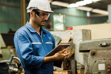 Maintenance engineer industrial plant with a tablet in hand and document plan, Engineer looking of working at industrial machinery setup in factory.