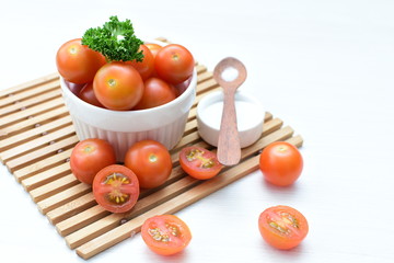 Fresh cherry tomato, displayed in containers on wooden background