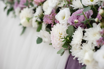 Close up of beautiful and stylish bouquet of white and purple roses, and eucalyptus greenery on holiday table. Summer floral composition. copy space