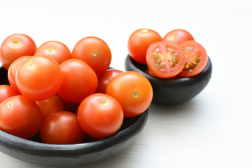 Fresh cherry tomato, displayed in containers on white wooden background