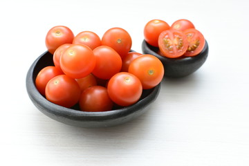 Fresh cherry tomato, displayed in containers on white wooden background