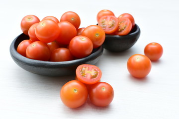 Fresh cherry tomato, displayed in containers on white wooden background
