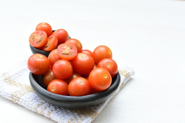 Fresh cherry tomato, displayed in containers on white wooden background
