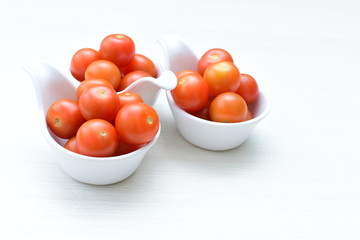 Fresh cherry tomato, displayed in containers on white wooden background