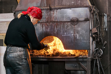 woman blacksmith near a flaming forge furnace