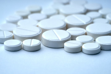 Closeup of white pills on a white background with texture.