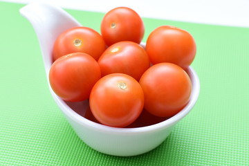 Fresh cherry tomato, displayed in containers on colorful colors background