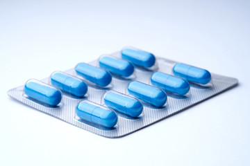 Closeup of blue pills in packaging on a white background with texture.