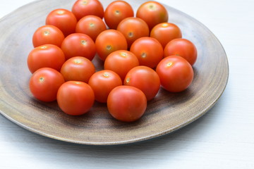 Fresh cherry tomato, displayed in containers on white wooden background