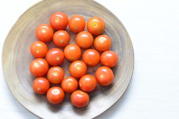 Fresh cherry tomato, displayed in containers on white wooden background
