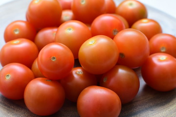 Fresh cherry tomato, displayed in containers on white wooden background
