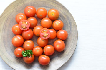 Fresh cherry tomato, displayed in containers on white wooden background