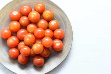 Fresh cherry tomato, displayed in containers on white wooden background