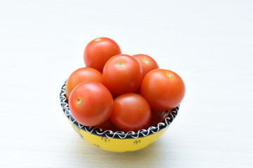 Fresh cherry tomato, displayed in containers on white wooden background