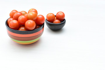 Fresh cherry tomato, displayed in containers on white wooden background