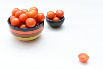 Fresh cherry tomato, displayed in containers on white wooden background