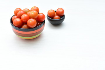 Fresh cherry tomato, displayed in containers on white wooden background