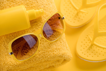 Sunscreen spray, towel, sunglasses, flip-flops