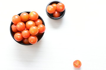 Fresh cherry tomato, displayed in containers on white wooden background