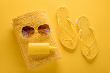 Sunscreen spray, towel, sunglasses, flip-flops