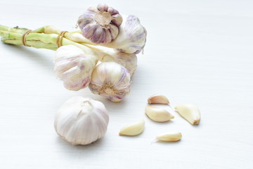 Heads of garlic, ripe white corsage on white wooden background