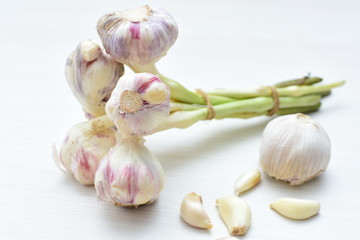 Heads of garlic, ripe white corsage on white wooden background