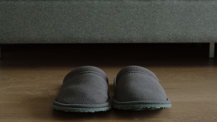 Slippers stands on a floor near a bed at home