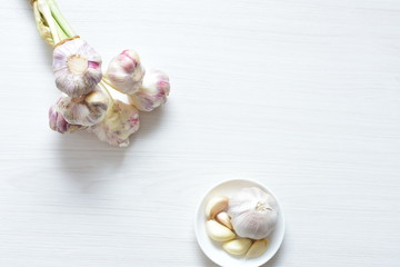 Heads of garlic, ripe white corsage on white wooden background