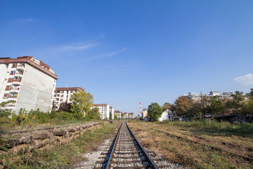 Fototapeta na wymiar Industrial landscape in Belgrade, Serbia, with a single railway track passing in the middle of industries while the chimney of a factory can be seen in background