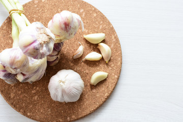 Heads of garlic, ripe white corsage on white wooden background