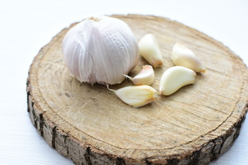 Heads of garlic, ripe white corsage on white wooden background