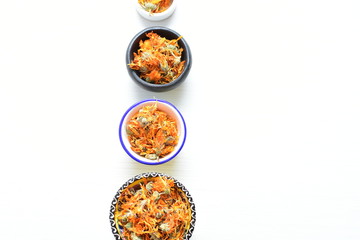 Petals of chopped dried calendula, displayed in containers on white wooden background