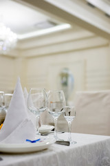 Server table plate knife fork and wine glasses at the banquet. Luxurious elegant dinner at the table in the restaurant. Holiday table decoration