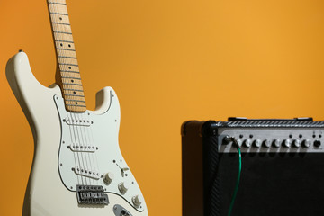 Naklejka premium Modern guitar and amplifier on color background