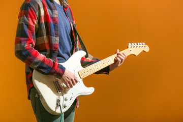 Young man playing guitar on color background