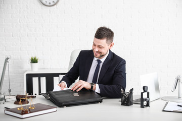 Male lawyer with briefcase sitting at workplace in office