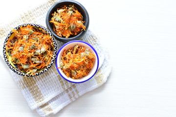 Petals of chopped dried calendula, displayed in containers on white wooden background