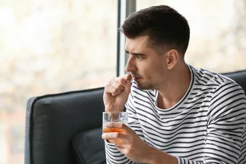 Poster Depressed young man drinking alcohol at home © Pixel-Shot