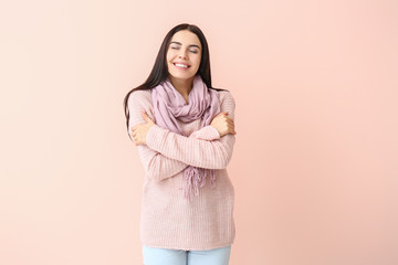 Obraz premium Beautiful young woman in warm sweater on color background